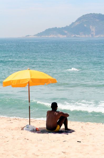 File:Man sitting under beach umbrella.JPG